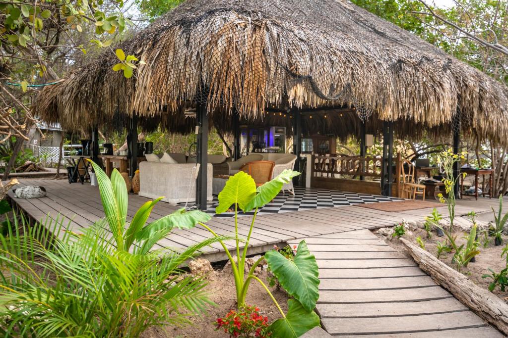 Tropical outdoor setting with a thatched-roof hut and wooden walkway.