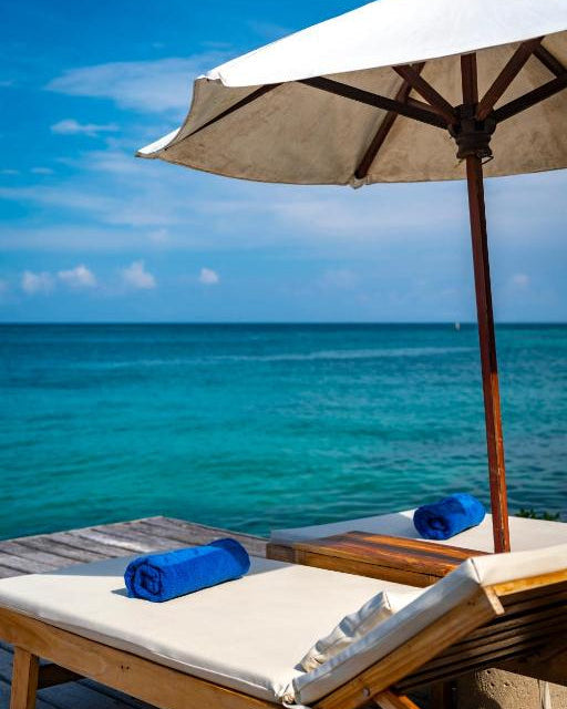 Beach scene with lounge chairs, umbrella, and towels by the ocean