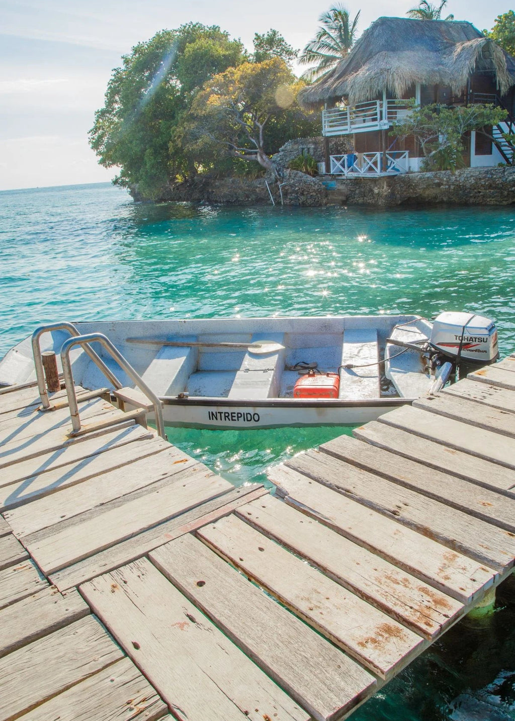 Boat docked at a wooden pier with a tropical resort in the background.