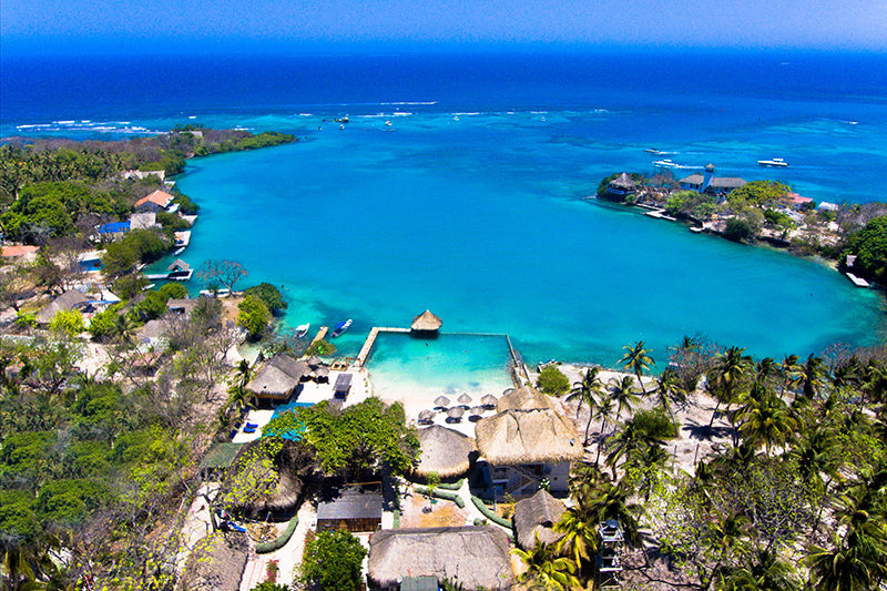 Aerial view of a tropical resort with clear blue water and palm trees.