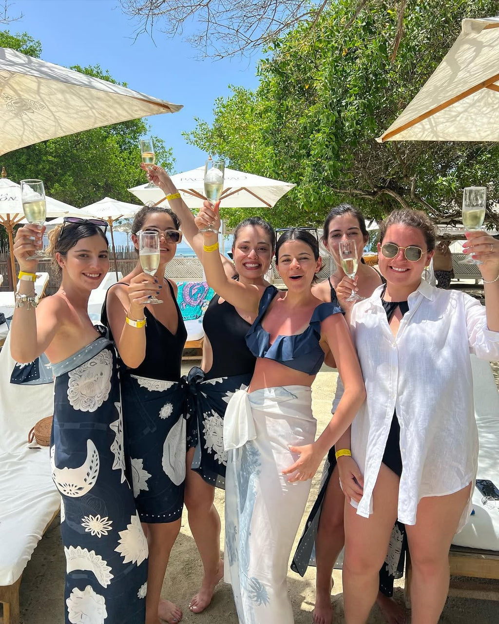 Group of women celebrating with champagne by a poolside