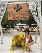 Woman posing with a large tortoise statue at Póo Pó Beach Club.