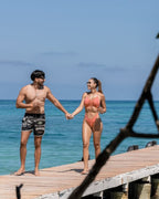 Two people holding hands on a wooden dock by the ocean.