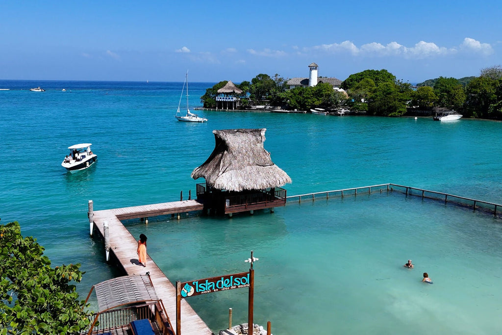 Tropical beach with turquoise water, wooden huts, and people enjoying the sun.