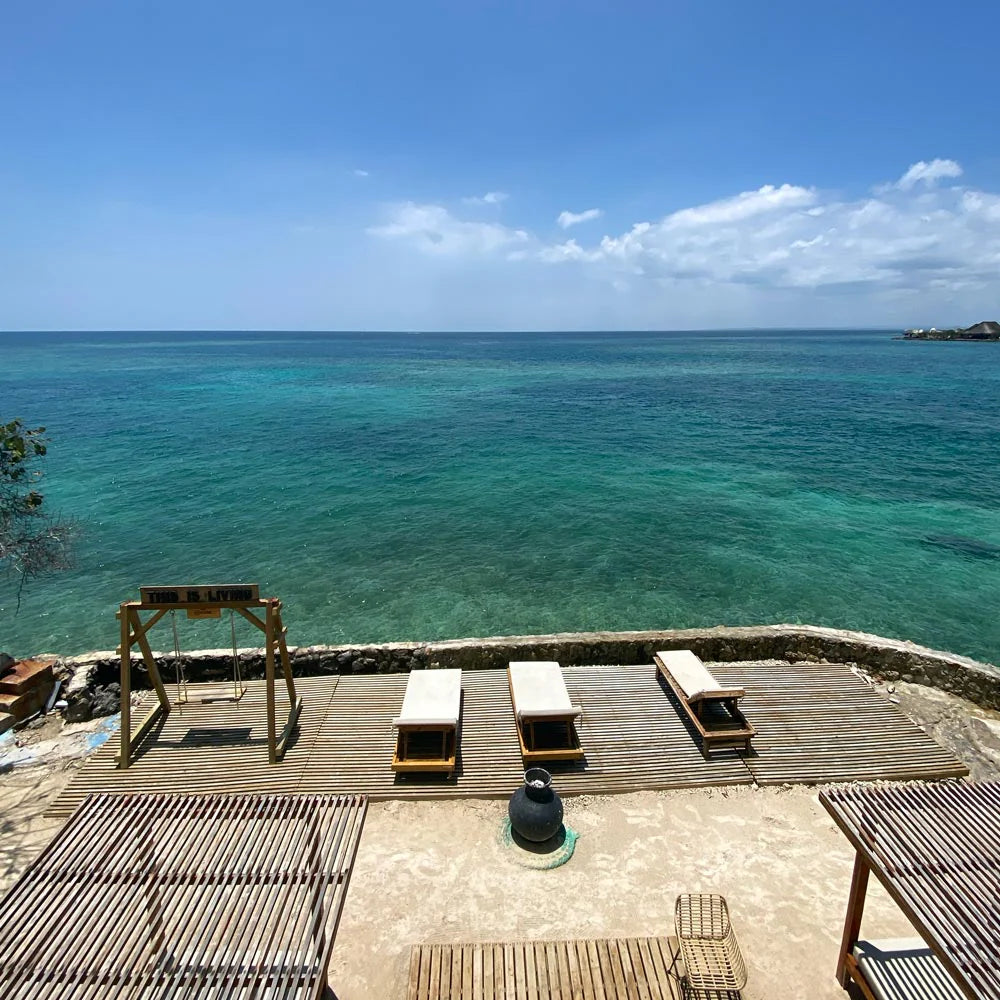 Wooden deck with lounge chairs overlooking a clear blue ocean