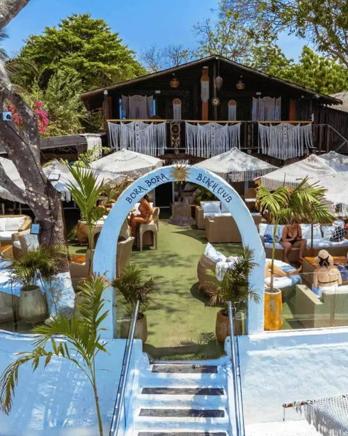 Outdoor setting with a pool, lounge chairs, and a building in the background.